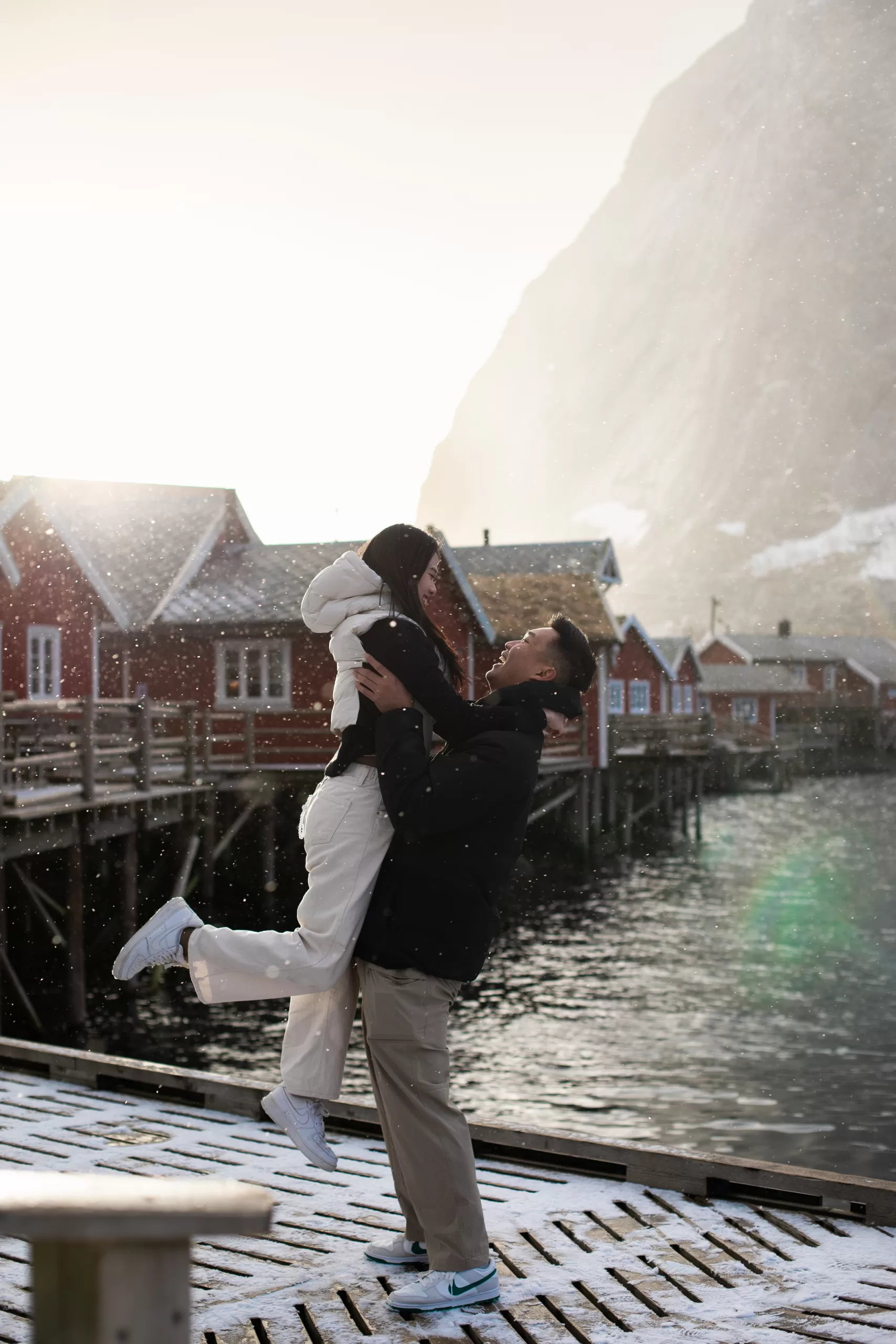 Romantic couple embracing in snowy Reine, Nusfjord, Lofoten – Arctic couple photography in winter light.