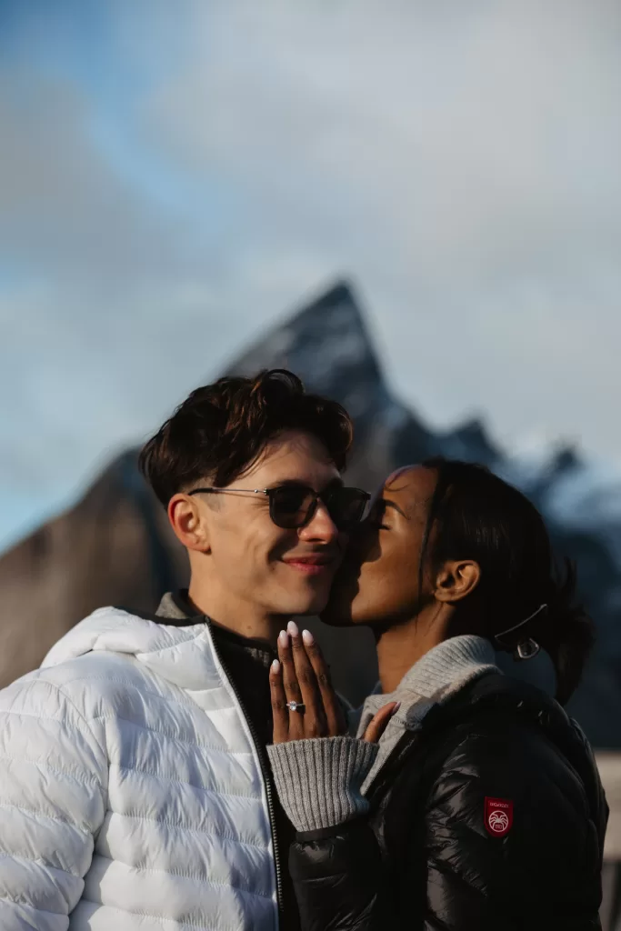 Couple celebrating engagement with joyful kiss in Arctic scenery. | 情侣在北极风光中庆祝订婚，喜悦地亲 | Paar feiert Verlobung mit freudigem Kuss in arktischer Landschaft. | คู่รักฉลองการหมั้นด้วยจูบแห่งความสุขในภูมิประเทศ