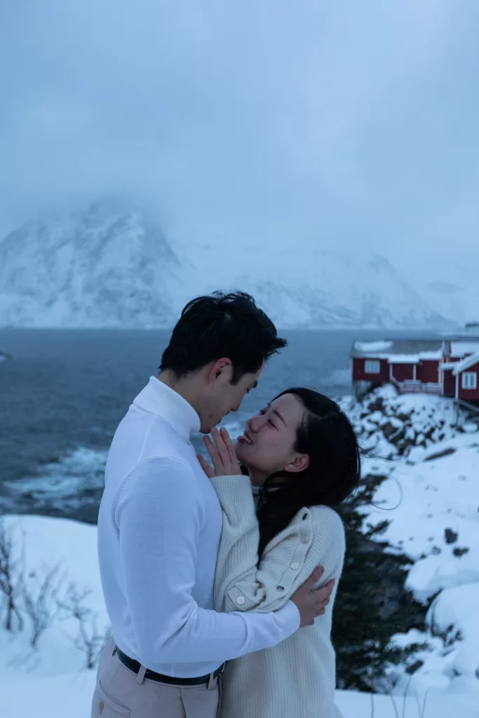 Emotional moment of a couple on the rocky Arctic coastline of Lofoten – cozy winter love story.