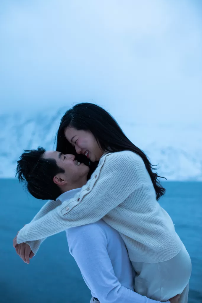 English: Joyful couple laughing during romantic winter engagement photos in Lofoten – Wedding photographer Lofoten Chinese (中文): 情侣在洛弗敦冬季订婚照中欢笑 – 洛弗敦婚礼摄影师 Thai (ไทย): คู่รักหัวเราะอย่างมีความสุขในเซสชั่นถ่ายภาพหมั้นฤดูหนาวที่โลโฟเทน – ช่างภาพแต่งงานโลโฟเทน German (Deutsch): Lachendes Paar bei einem romantischen Verlobungsshooting im Winter in Lofoten – Hochzeitsfotograf Lofoten